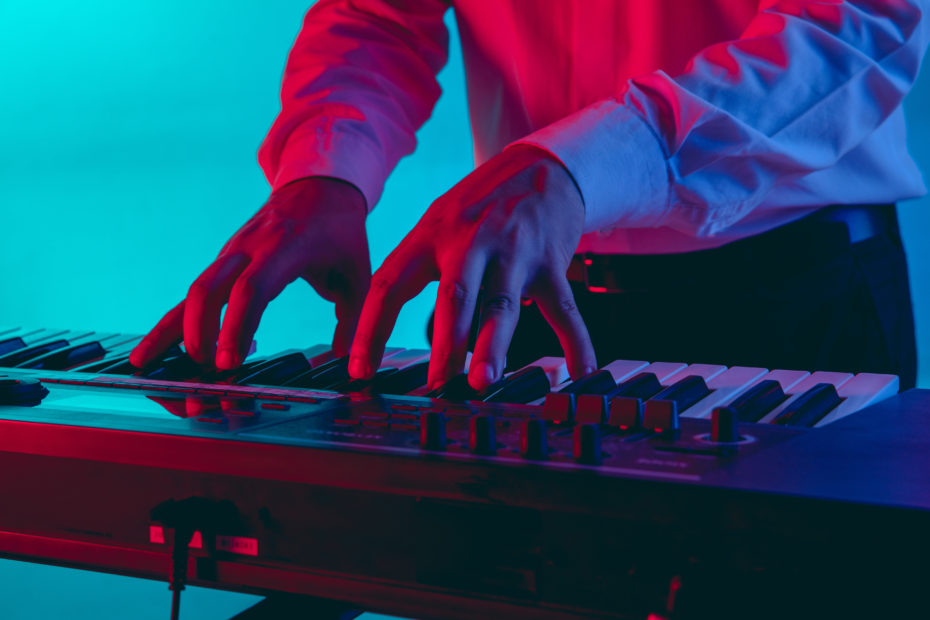 Musicista che suona una tastiera con illuminazione rosso blu