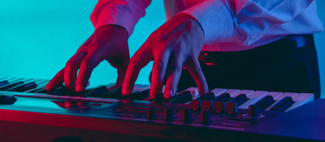 Musicista che suona una tastiera con illuminazione rosso blu