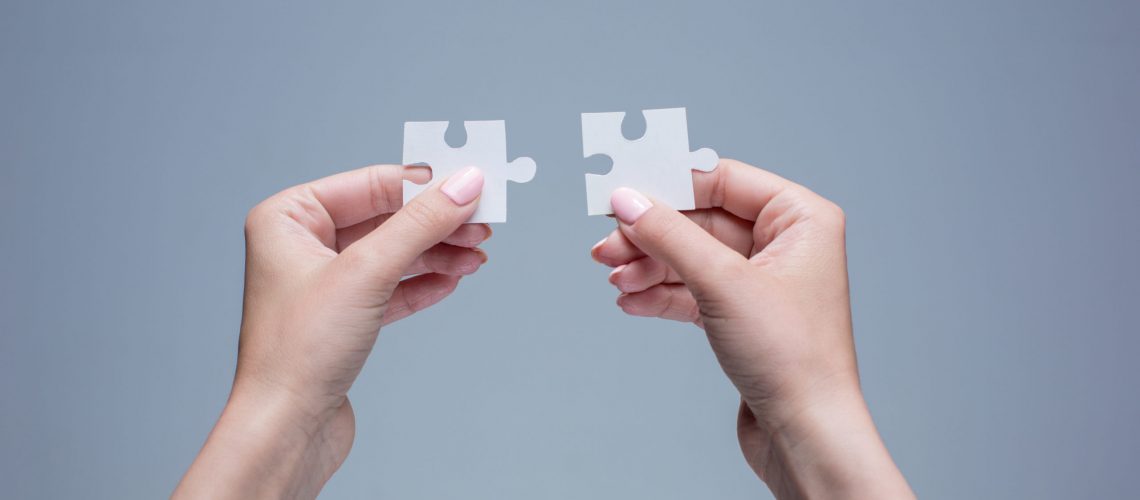 Due mani tengono due pezzi di puzzle